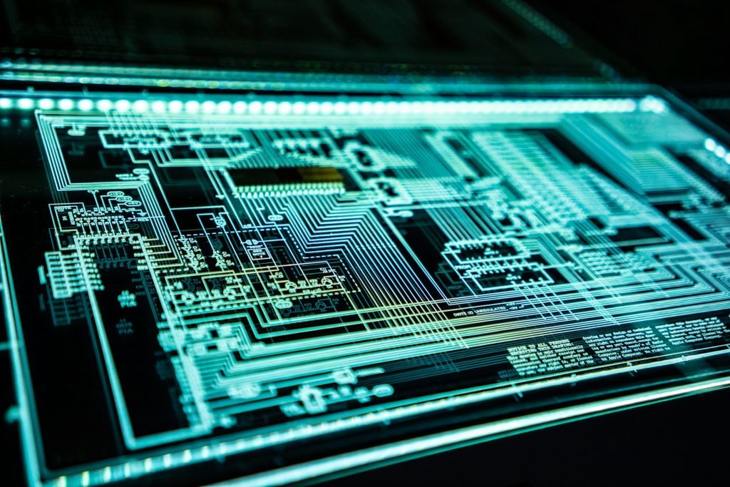 Glowing teal electronic circuit schematic diagram displayed on a dark backlit glass screen